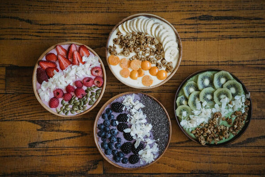 Four different acai bowls on a wooden table