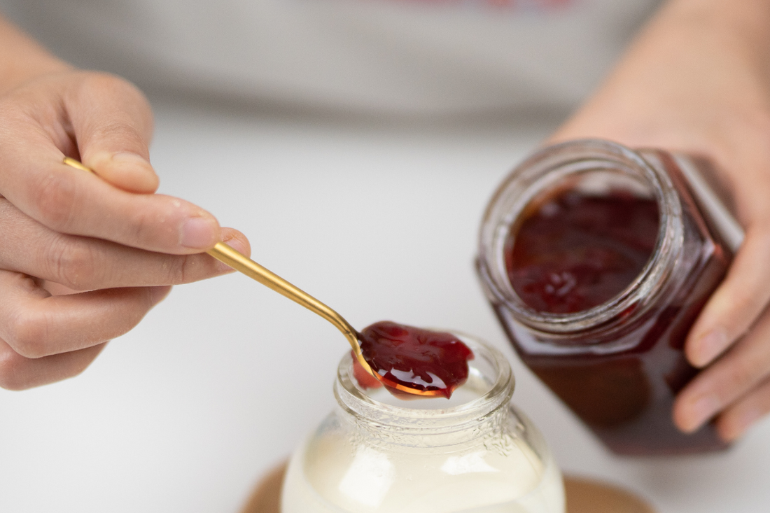 A woman adding flavored sea moss gel to her yogurt