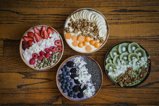 Four different acai bowls on a wooden table